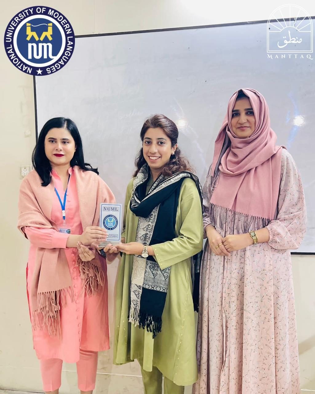Sara Ishaq receiving a shield as guest speaker at the National University of Modern Languages